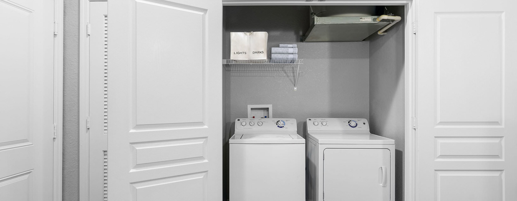 shelving in laundry closet with side-by-side washer/dryer units